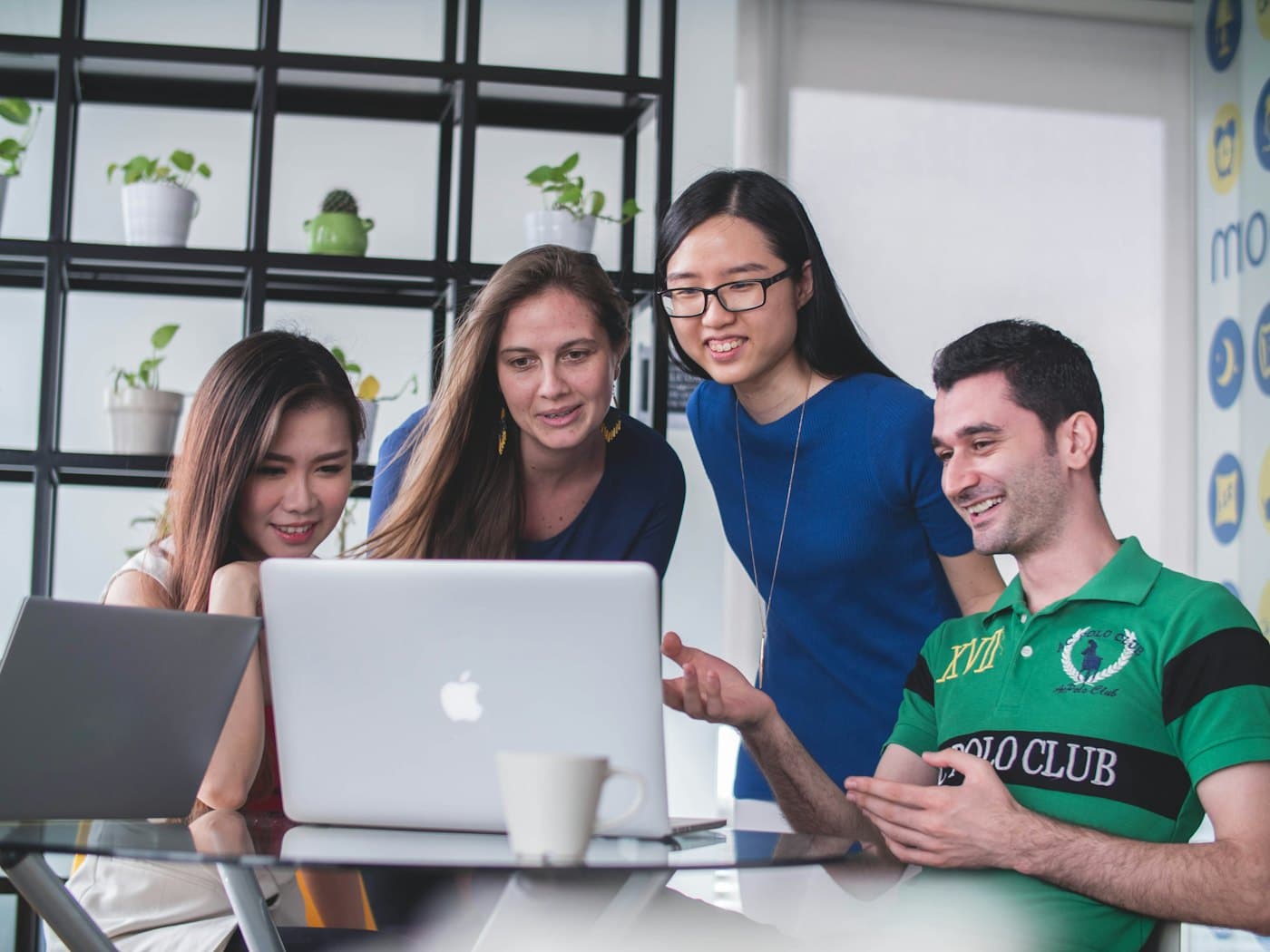 Four early-career colleagues working together around a laptop
