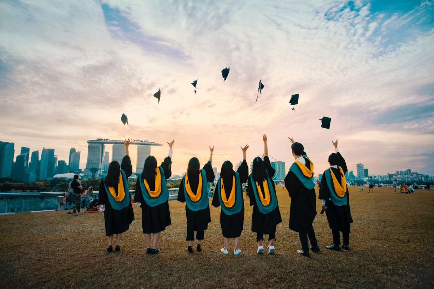 Graduates throwing their caps in the air with a city skyline behind them